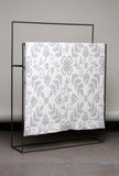 Fabric with a floral pattern on a black metal stand against a gray background