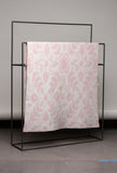 Floral-patterned blanket on a black metal rack against a gray background