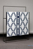 Patterned blanket on a black metal stand against a gray background