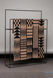 Patterned blanket on a black metal rack against a gray background