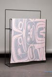Textile with abstract pattern on a black stand against a gray wall