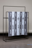 Textile with animal pattern draped over a black metal rack against a neutral background