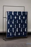 Navy blue blanket with white animal pattern draped over a black metal rack against a gray wall.