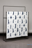 Blanket with black animal pattern on a metal rack against a gray wall.