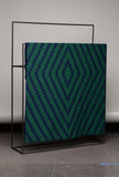 Green and blue patterned fabric on a black metal frame against a white wall.