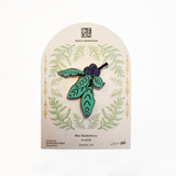 An enamel pin shaped like blue huckleberries with green leaves, mounted on a branded Eighth Generation display card against a white background.