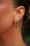 Close-up of an ear wearing a gold and white geometric earring with a blurred background