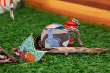 A round magnet featuring a waterfall with the text 'Snoqualmie Falls' on it, displayed on green artificial grass with a small red lantern and wooden branch props.