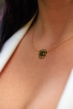 Close-up of a necklace with a green pendant on a person's neck.