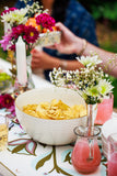 Bowl of snacks on a table with flowers and drinks