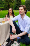 Man and woman sitting outdoors at a table with drinks, surrounded by greenery.