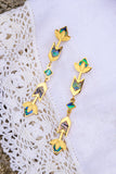 Gold earrings with colorful stones on a white lace fabric background