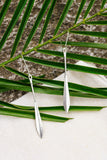 Silver earrings on a leaf with a natural background