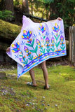 Person holding a colorful floral towel outdoors with greenery in the background