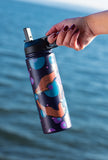 Hand holding a colorful water bottle with a blue background