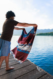Person holding a patterned towel by a lake