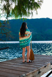 Person wrapped in a colorful towel standing on a dock by a lake