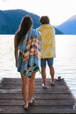 Two people standing on a dock by a lake, one holding a colorful towel.