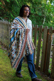 model walking in woods with blanket draped on his shoulder.