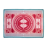A rectangular woven textile with a symmetrical geometric and floral pattern, featuring a central red and pink circular motif with white accents, bordered by pink and light blue stripes, and finished with a teal blue edge.