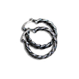 A pair of silver-toned twisted cable hoop earrings with a polished finish, shown on a plain white background.
