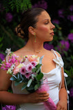 Woman in a white dress holding a bouquet of flowers with a blurred floral background